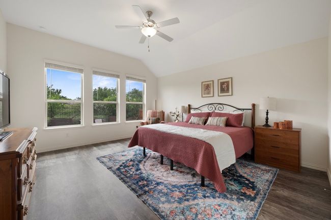 Bedroom with lofted ceiling, wood finished floors, baseboards, and a ceiling fan | Image 12
