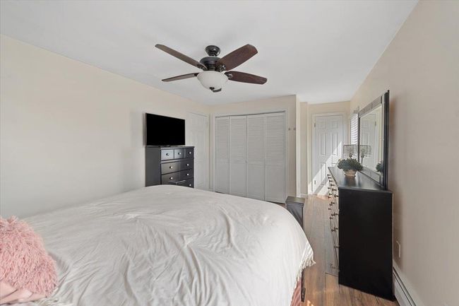 Bedroom featuring a baseboard radiator, ceiling fan, and dark wood-style flooring | Image 11