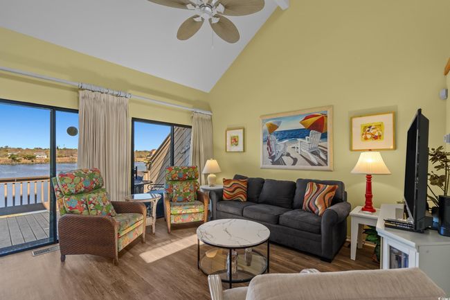 Living area featuring wood finished floors, visible vents, high vaulted ceiling, and ceiling fan | Image 9
