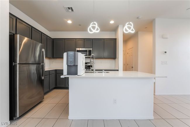 Kitchen featuring appliances with stainless steel finishes, backsplash, light countertops, light tile patterned floors, and recessed lighting | Image 14