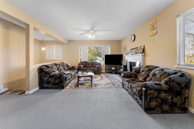 Living room with a fireplace, carpet, baseboards, and a ceiling fan | Image 10