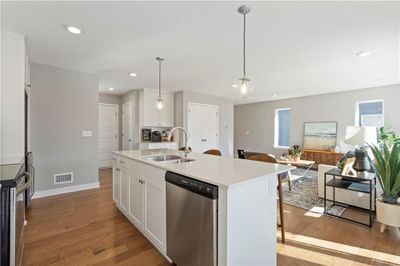 Kitchen featuring dishwasher, light hardwood / wood-style flooring, white cabinetry, sink, and a center island with sink | Image 3