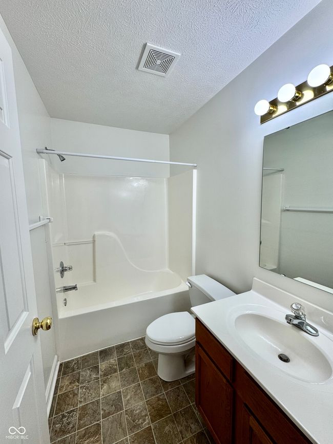 full bathroom featuring visible vents, toilet, a textured ceiling, bathing tub / shower combination, and vanity | Image 10