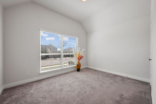 Carpeted empty room featuring baseboards and lofted ceiling | Image 26