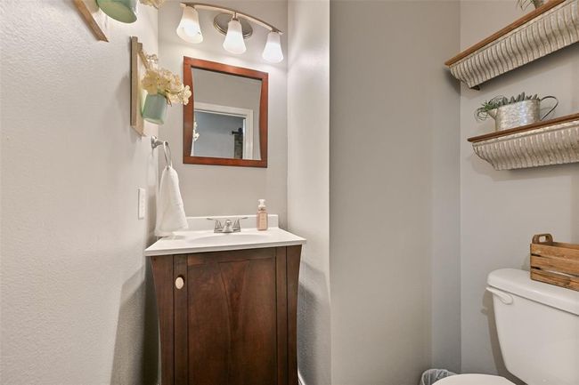 Charming half bath with a rich wood vanity, framed mirror, and updated lighting—perfectly placed for guests and everyday convenience. | Image 16