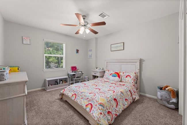 This cozy bedroom features a ceiling fan, and plush carpet. It includes a window to allow plenty natural light. | Image 30