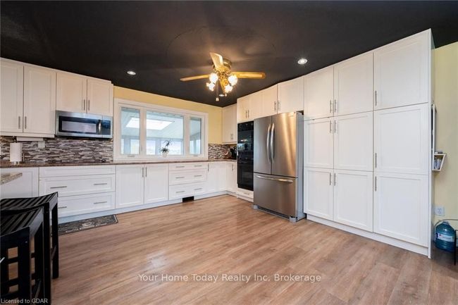 Kitchen with tasteful backsplash, white cabinetry, and appliances with stainless steel finishes | Image 11
