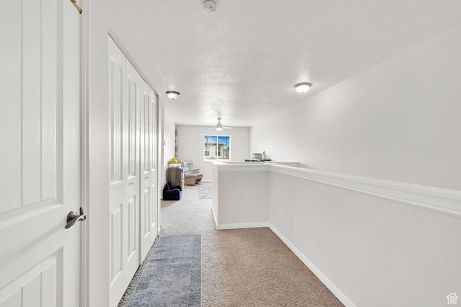Hallway with carpet flooring, a textured ceiling, and baseboards | Image 16
