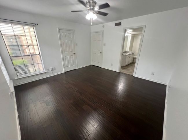 Unfurnished bedroom with connected bathroom, dark wood-style floors, baseboards, and visible vents | Image 16