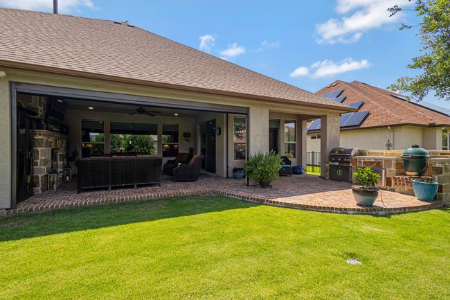 Back of property with an outdoor kitchen, a yard, an outdoor hangout area, a ceiling fan, and a patio | Image 34