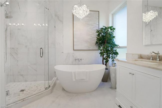Bathroom featuring an inviting chandelier, marble finish floor, a freestanding bath, and a stall shower | Image 16