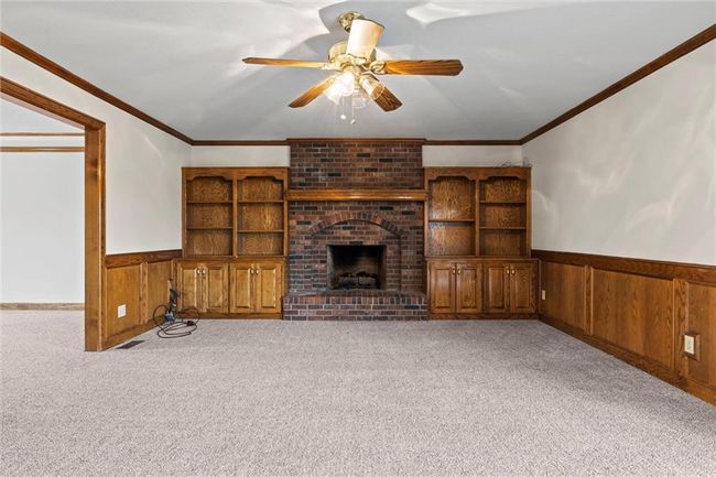 Unfurnished living room with light colored carpet, a brick fireplace, ceiling fan, and ornamental molding | Image 11