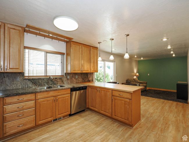 Kitchen with stainless steel dishwasher, open floor plan, a sink, a peninsula, and tasteful backsplash | Image 10