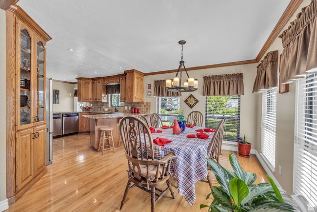 Dining room featuring light wood-style flooring, plenty of natural light, crown molding, a chandelier, and recessed lighting | Image 11