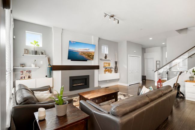 Living area featuring stairs, a fireplace, dark wood-style flooring, and baseboards | Image 7