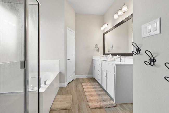 Bathroom with double vanity, a bath, wood finished floors, and a stall shower | Image 11