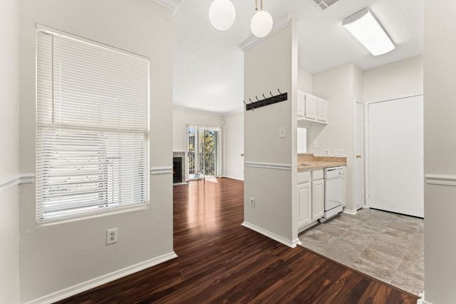 Kitchen with a warm lit fireplace, wood finished floors, white cabinetry, white dishwasher, and light countertops | Image 8