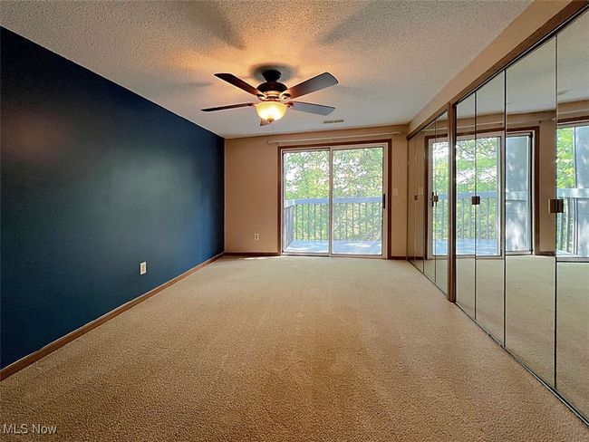 Master bedroom with carpet floors, ceiling fan, healthy amount of natural light, and access to balcony with tree top views | Image 9