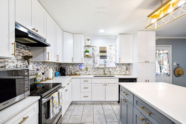 Kitchen featuring under cabinet range hood, appliances with stainless steel finishes, gray cabinetry, plenty of natural light, and a textured ceiling | Image 7