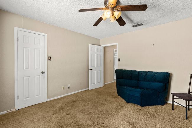 Living area featuring a ceiling fan, a textured ceiling, visible vents, and carpet | Image 16