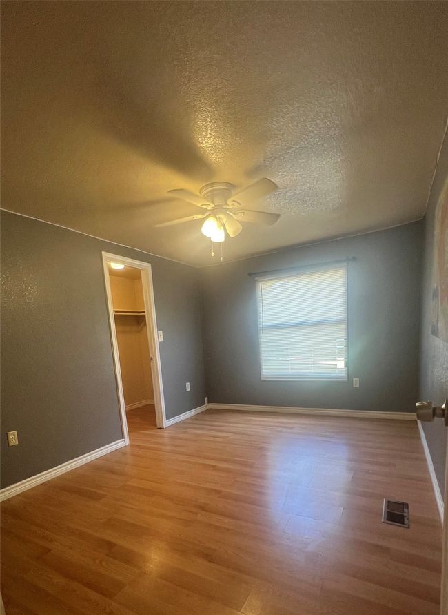 Unfurnished room with wood finished floors, a ceiling fan, and a textured ceiling | Image 13