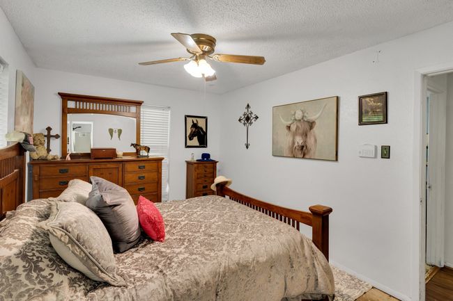 Bedroom with light wood-type flooring, a textured ceiling, ceiling fan, and baseboards | Image 12