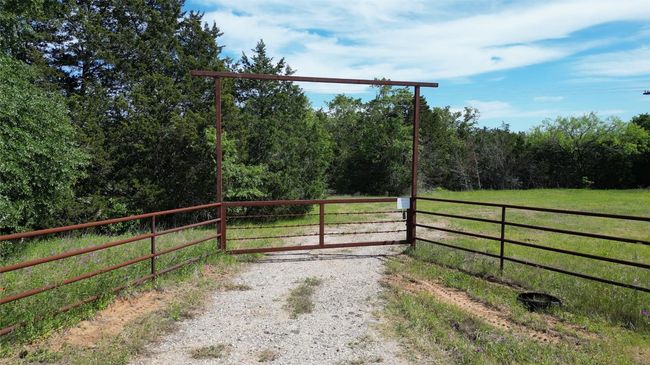 View of gate featuring a lawn and a wooded view | Image 4