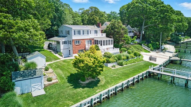 Rear view of house with a water view, a chimney, stairway, a lawn, and brick siding | Image 12