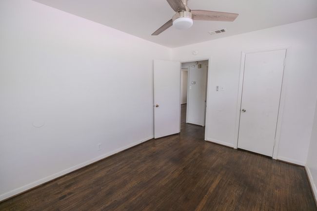 Unfurnished bedroom featuring baseboards, ceiling fan, dark wood-style flooring, and visible vents | Image 9