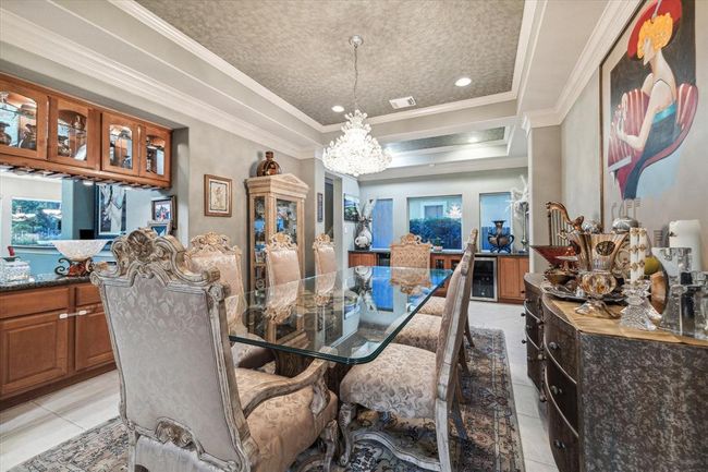 Spacious Dining Room is highlighted by a Tiffany's chandelier & faux painting in the trey ceiling. This space also offers two wine fridges as seen under the windows. | Image 22