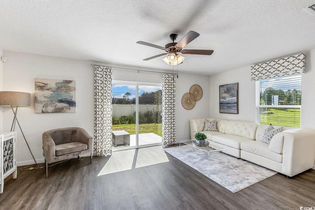 Living area with healthy amount of natural light, wood finished floors, ceiling fan, and a textured ceiling | Image 8