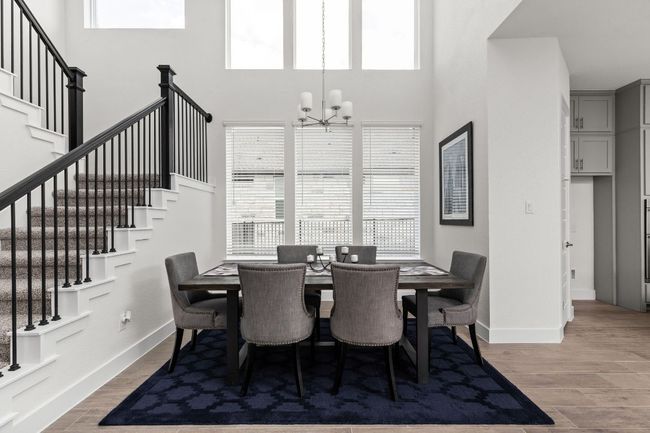 Dining area with stairway, a chandelier, a high ceiling, baseboards, and light wood-style floors | Image 9