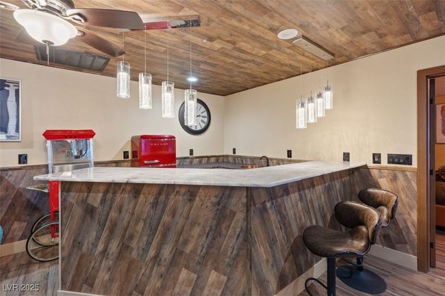 Bar featuring wainscoting, wooden ceiling, wood finished floors, and wet bar | Image 43