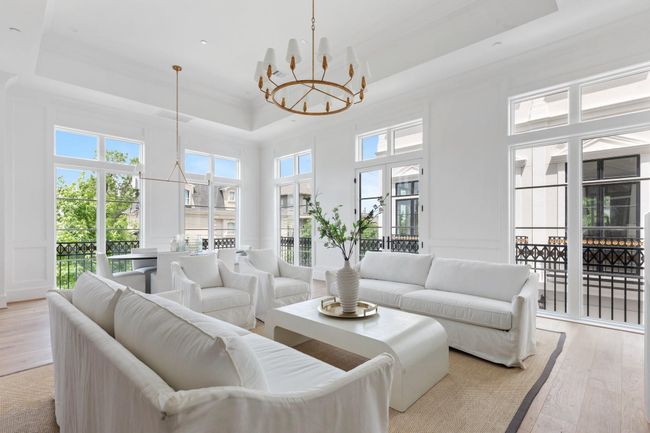 Soaring 14’ ceilings crown the second-floor living room, where a cast stone fireplace and custom millwork create an unforgettable first impression. | Image 4
