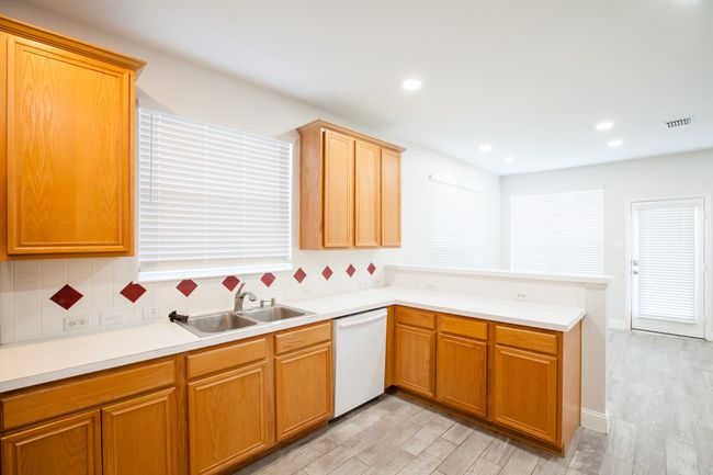 Kitchen featuring dishwasher, a peninsula, light wood-style floors, decorative backsplash, and recessed lighting | Image 12