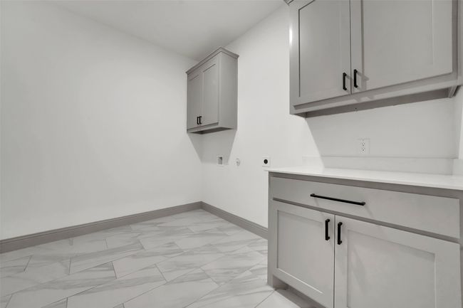 Clothes washing area featuring hookup for an electric dryer, baseboards, hookup for a washing machine, cabinet space, and marble finish floor | Image 18