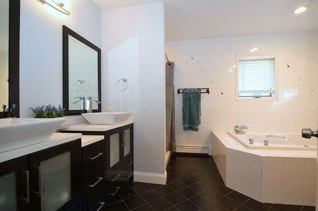 Bathroom featuring a stall shower, vanity, tile patterned flooring, a bath, and a baseboard heating unit | Image 18
