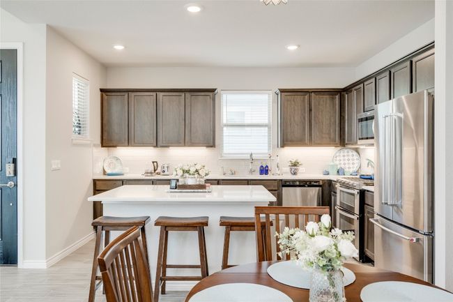 Kitchen with light countertops, tasteful backsplash, a center island, a breakfast bar, and appliances with stainless steel finishes | Image 11