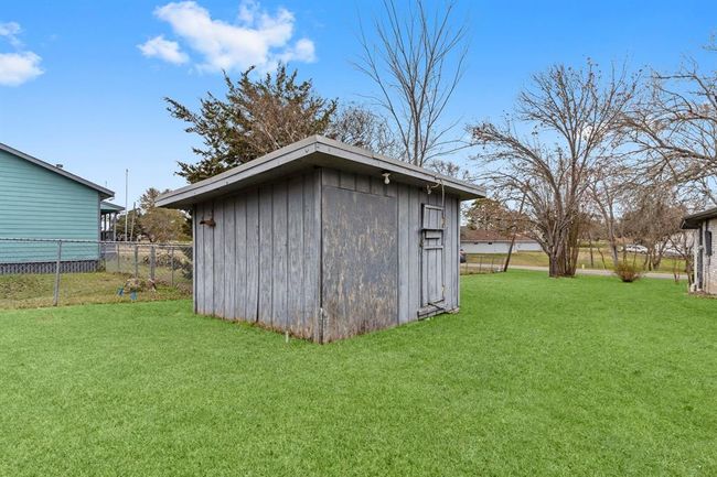 The yard is enclosed by a chain-link fence and features a wooden shed, surrounded by trees, offering ample storage space. | Image 35