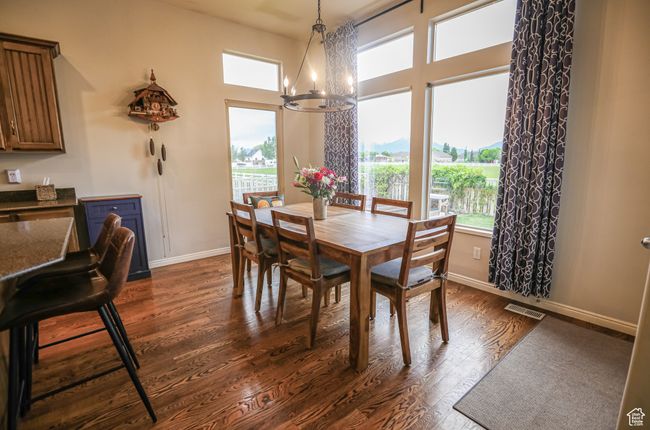 Dining area with a chandelier, dark wood-style flooring, and baseboards | Image 9