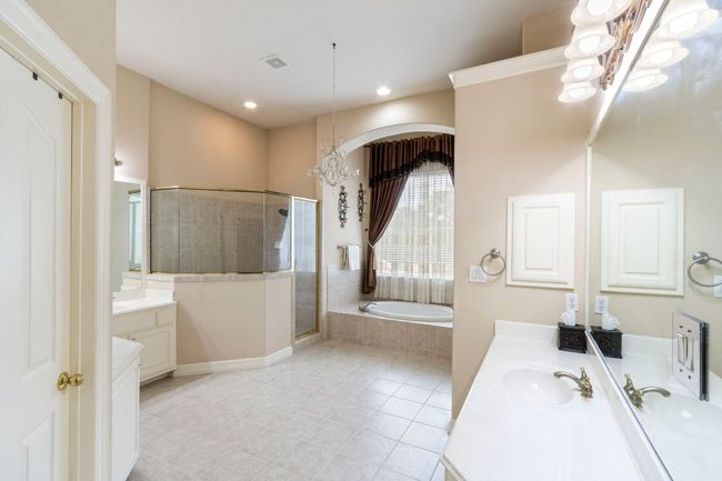 Bathroom with vanity, a chandelier, a garden tub, a stall shower, and tile patterned floors | Image 23