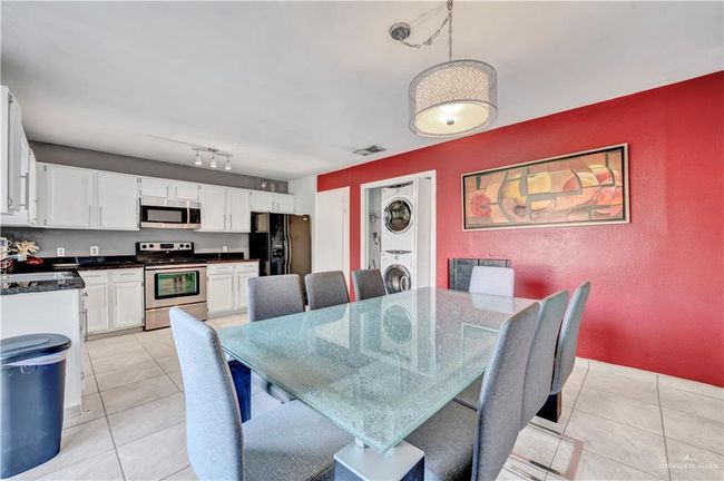 Dining area featuring stacked washer and clothes dryer, light tile patterned floors, and a textured wall | Image 4