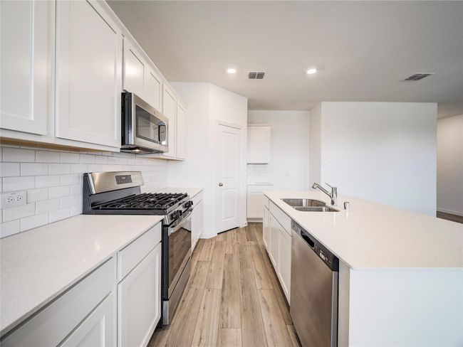 Kitchen with appliances with stainless steel finishes, a sink, light wood-style floors, backsplash, and recessed lighting | Image 5
