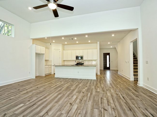 Unfurnished living room featuring light wood-style floors, stairs, a ceiling fan, and recessed lighting | Image 4