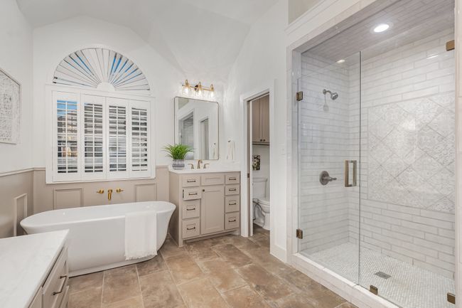 Full bath featuring vanity, vaulted ceiling, a stall shower, a soaking tub, and wainscoting | Image 20