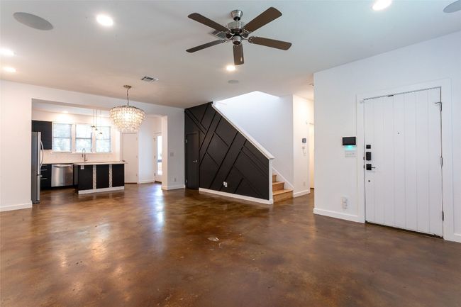 Unfurnished living room featuring finished concrete flooring, stairway, ceiling fan, a chandelier, and recessed lighting | Image 7