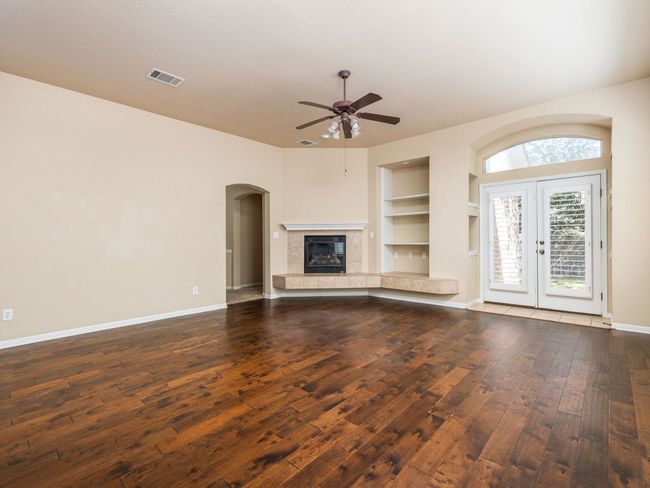 The living room has hardwood floors, a fireplace and ceiling fan, great for entertaining in all seasons. | Image 9