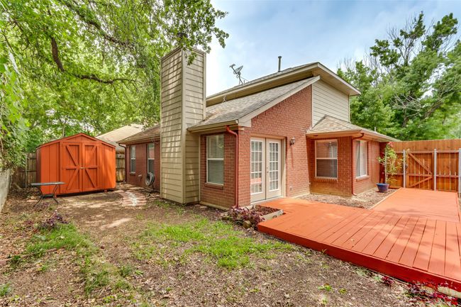 Rear view of property with a storage shed, brick siding, a fenced backyard, a wooden deck, and a chimney | Image 25