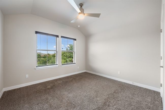 Carpeted spare room featuring vaulted ceiling and a ceiling fan | Image 29
