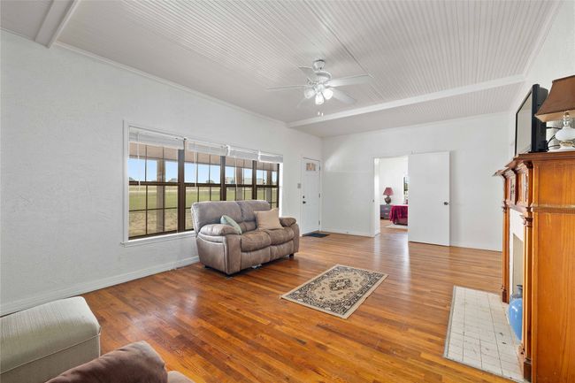 Living room with a ceiling fan, wood finished floors, crown molding, and wooden ceiling | Image 11